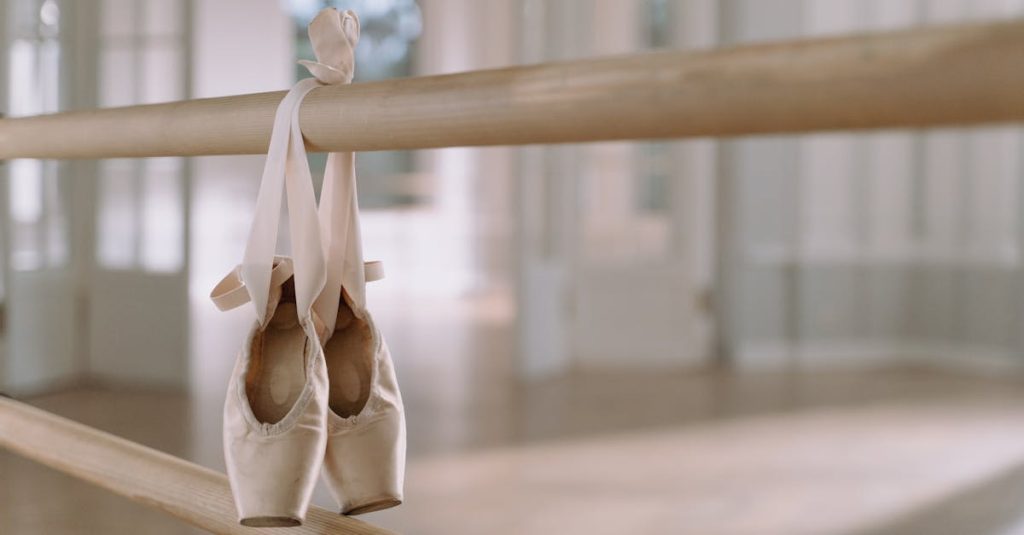 Close-up of ballet pointe shoes hanging on a barre in a dance studio.